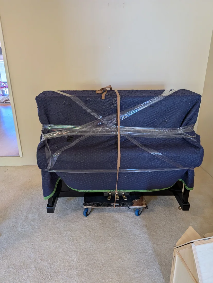Upright piano protected with moving blankets and secured for transport